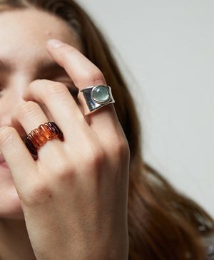 sienna brown ring on ring finger with hand holding up hand in front of face